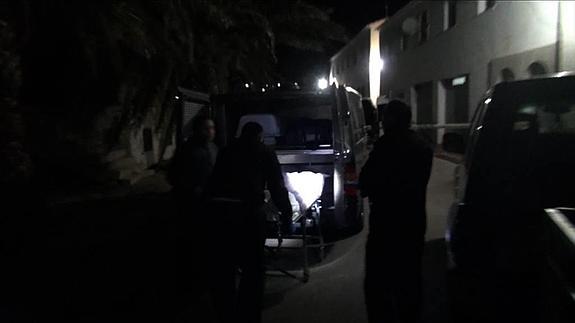 Operarios de la funeraria levantan el cadáver de la joven. 