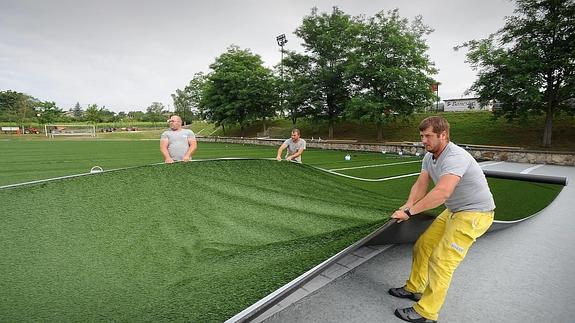 Unos operarios colocan césped artificial en una instalación. 