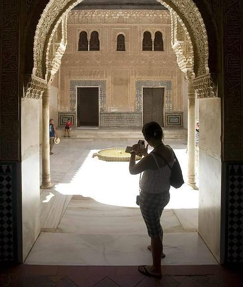 Una visitante toma una fotografía durante una visita a los palacios nazaríes del conjunto monumental de la Alhambra.  