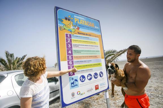 Dos motrileños junto a su perra Mai se informan sobre las normas de uso de la playa canina en El Cable.