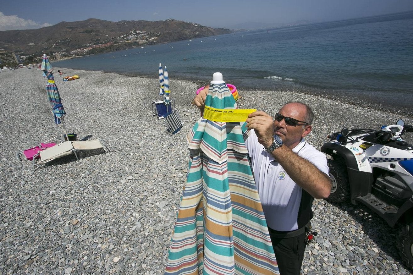 Un policía local asignado a Medio Ambiente precinta, ayer, una sombrilla abandonada en la playa sexitana de Velilla, actuación que se realizará durante esta semana.