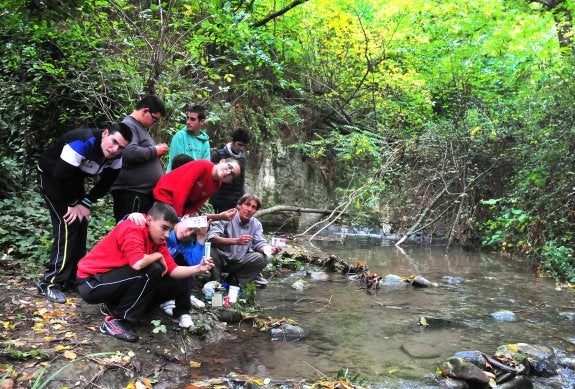 Un grupo de alumnos de educación especial de la Casa Madre del Ave María analizan la calidad del agua del río Darro, junto a su profesor.