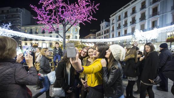 Un grupo de jóvenes se fotografía con el alumbrado navideño