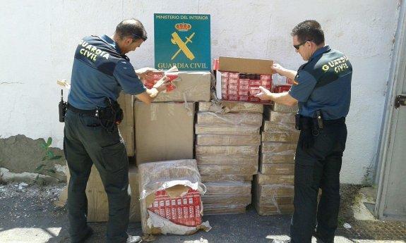Agentes de la Guardia Civil muestran las cajetillas de tabaco de contrabando incautadas en una operación.