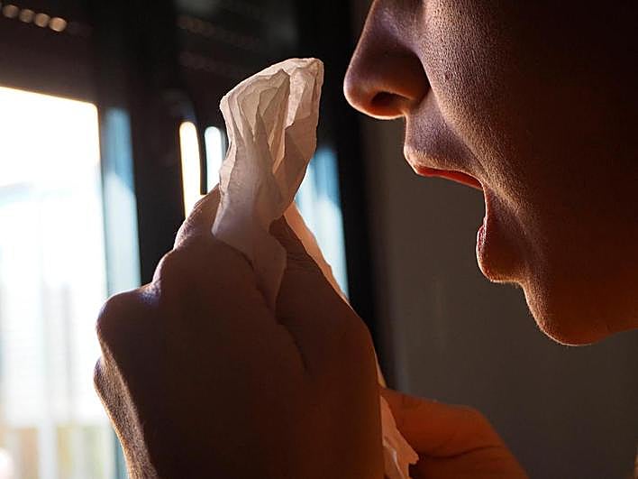 Una mujer estornuda a causa de la alergia primaveral.