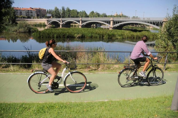 Dos personas montan en bicicleta en las inmediaciones del río.