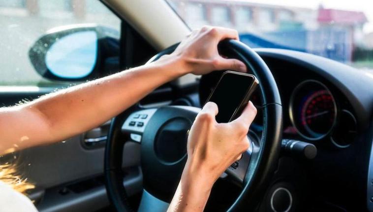 Una persona con el móvil al volante.