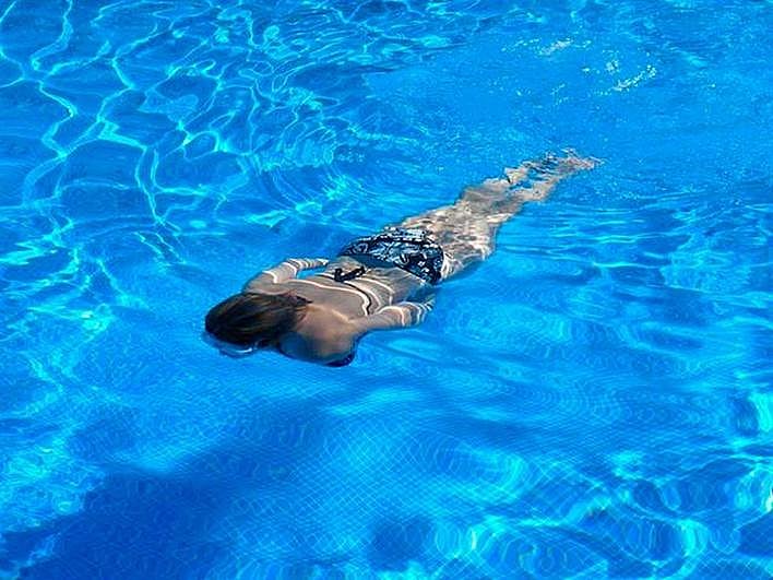 Una mujer nada en una piscina.