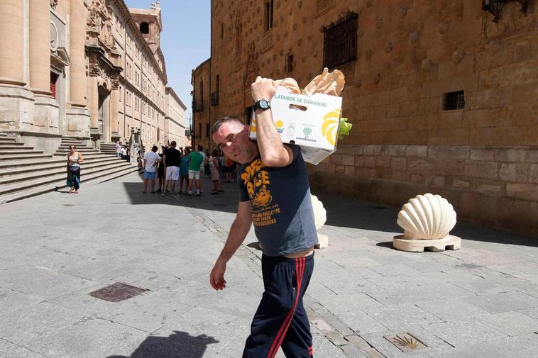 Un repartidor lleva una caja con alimentos por la calle Compañía.