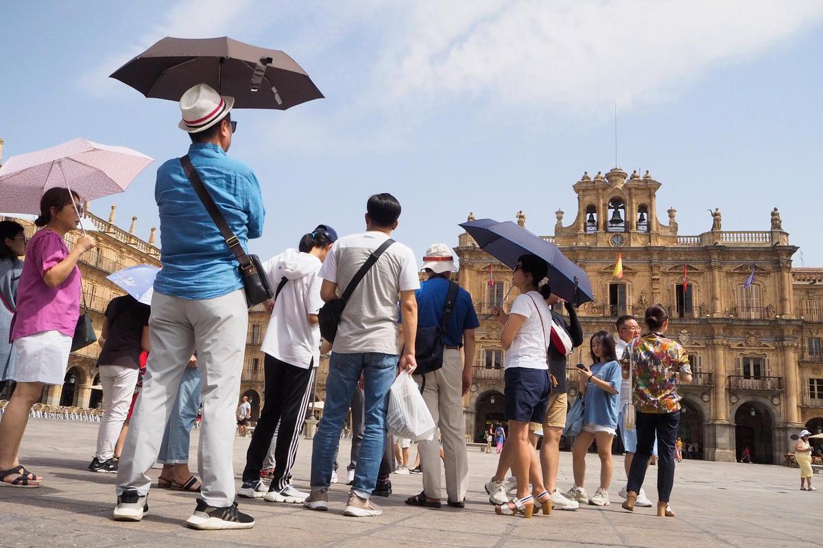 Varios turistas se protegen del sol en la Plaza Mayor de Salamanca.