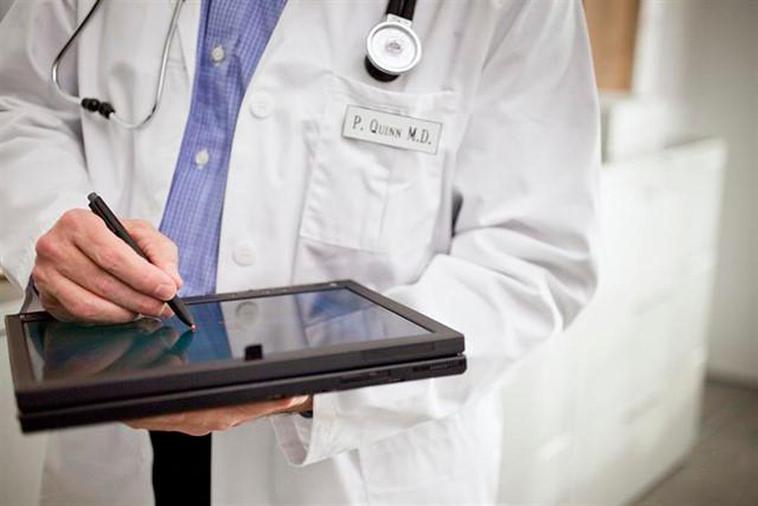 Un médico escribiendo en su tablet.