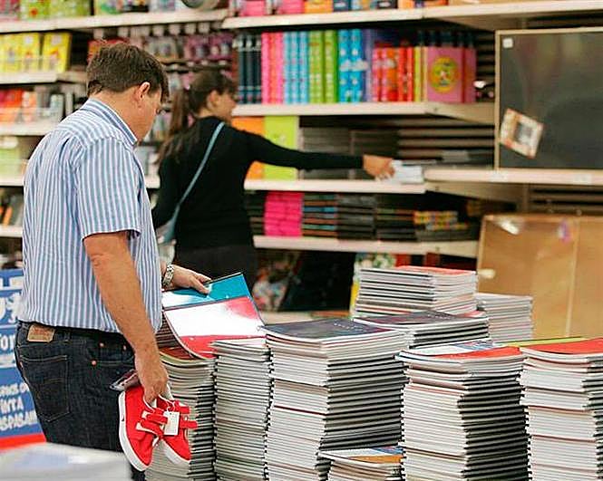 Un hombre hojea un cuaderno con unas deportivas rojas en la mano.