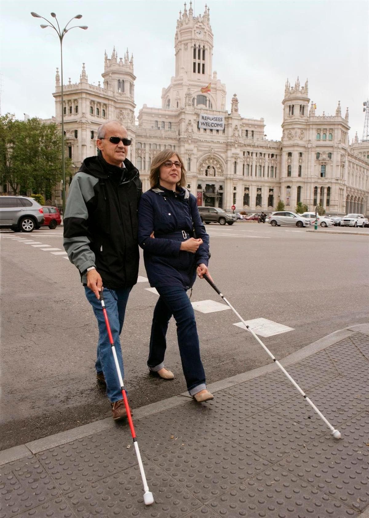 Dos personas caminan por la calle con sus bastones.