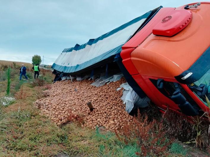 El camión cargado de patatas, volcado en la cuneta.