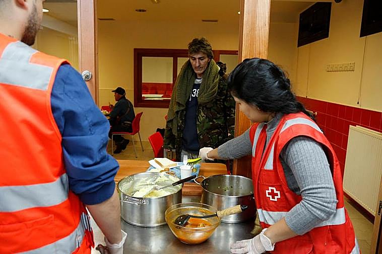 Un voluntario sirve la comida que se presta cada noche en el Centro de Personas Sin Hogar.