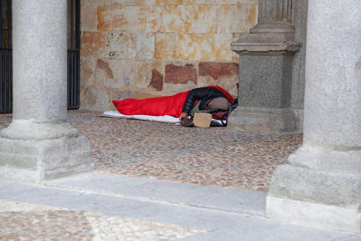 Un hombre duerme al raso en las galerías al aire libre del convento de San Esteban.