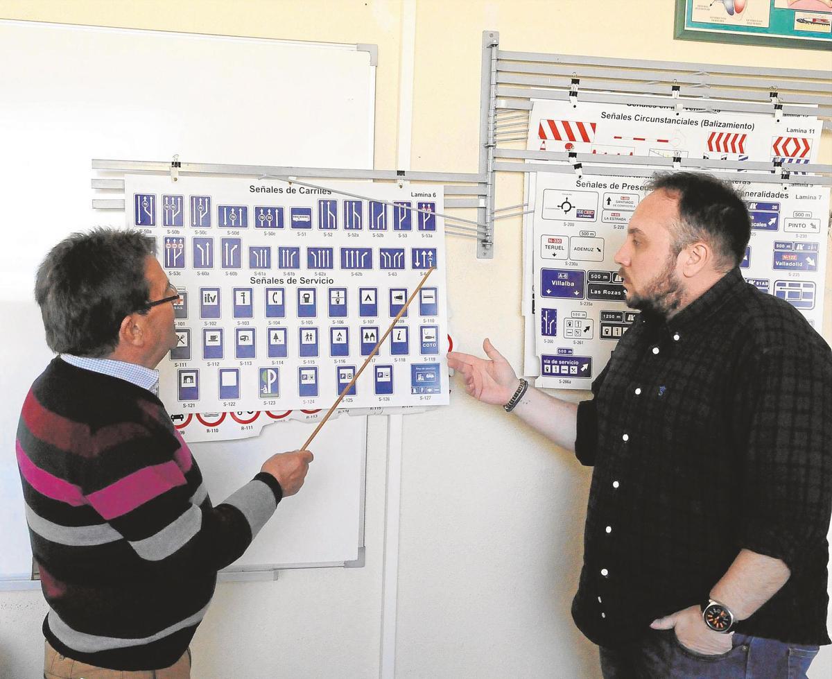 Dos profesores de autoescuela muestran las señales de tráfico.