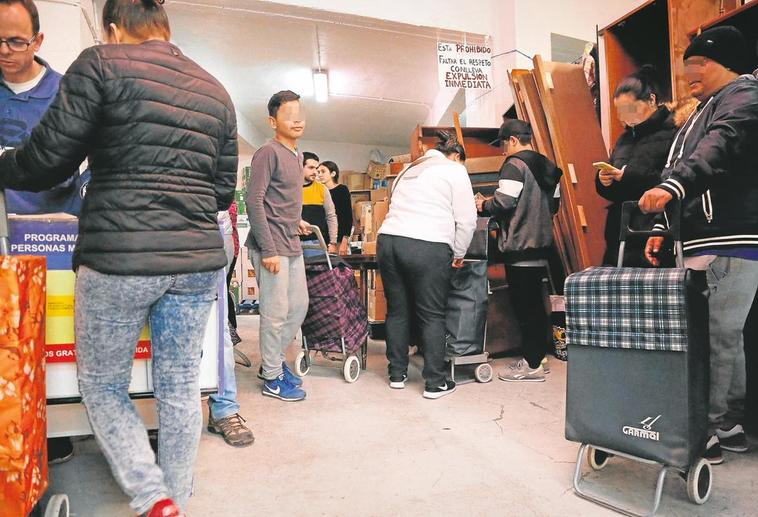 Colas el pasado sábado de personas migrantes en el almacén de la ONG Cajas Solidarias para recibir alimentos.