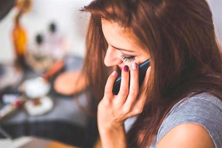 Una mujer habla a través de un telégono móvil.