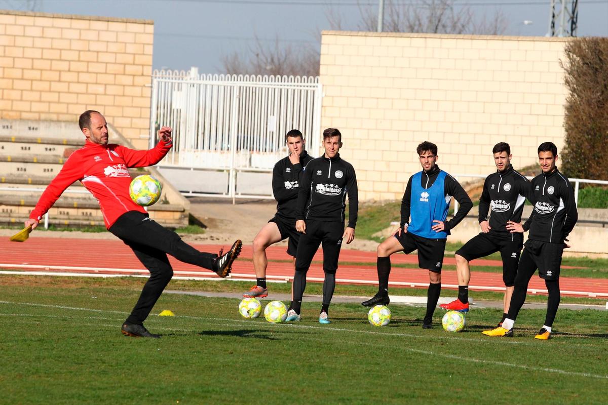 Jabi Luaces golpea un balón en un entrenamiento en Las Pistas ante la atenta mirada de sus futbolistas.