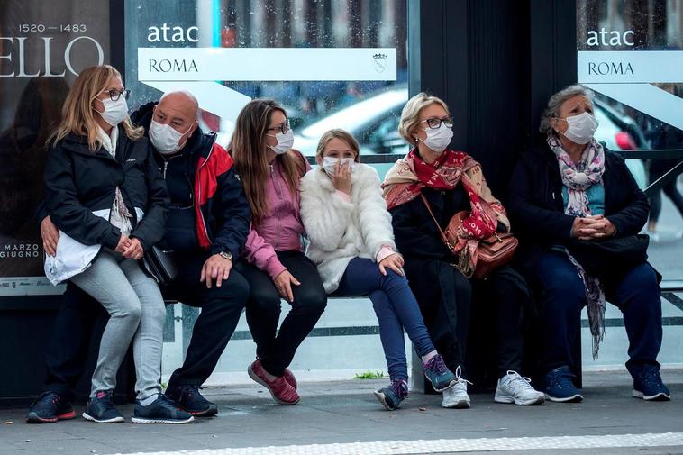 Varias personas en una parada de autobús en Roma.