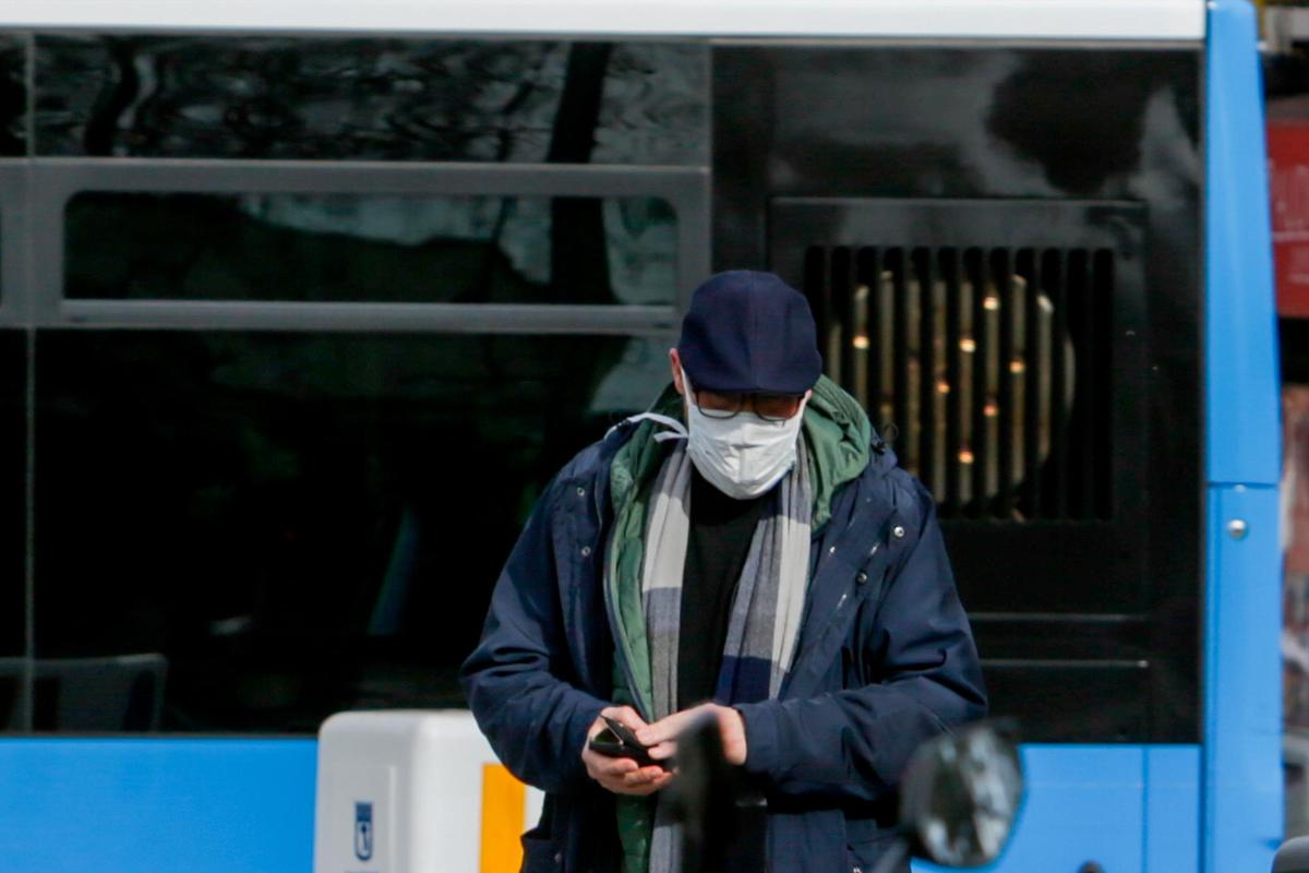 Una persona camina con una mascarilla.