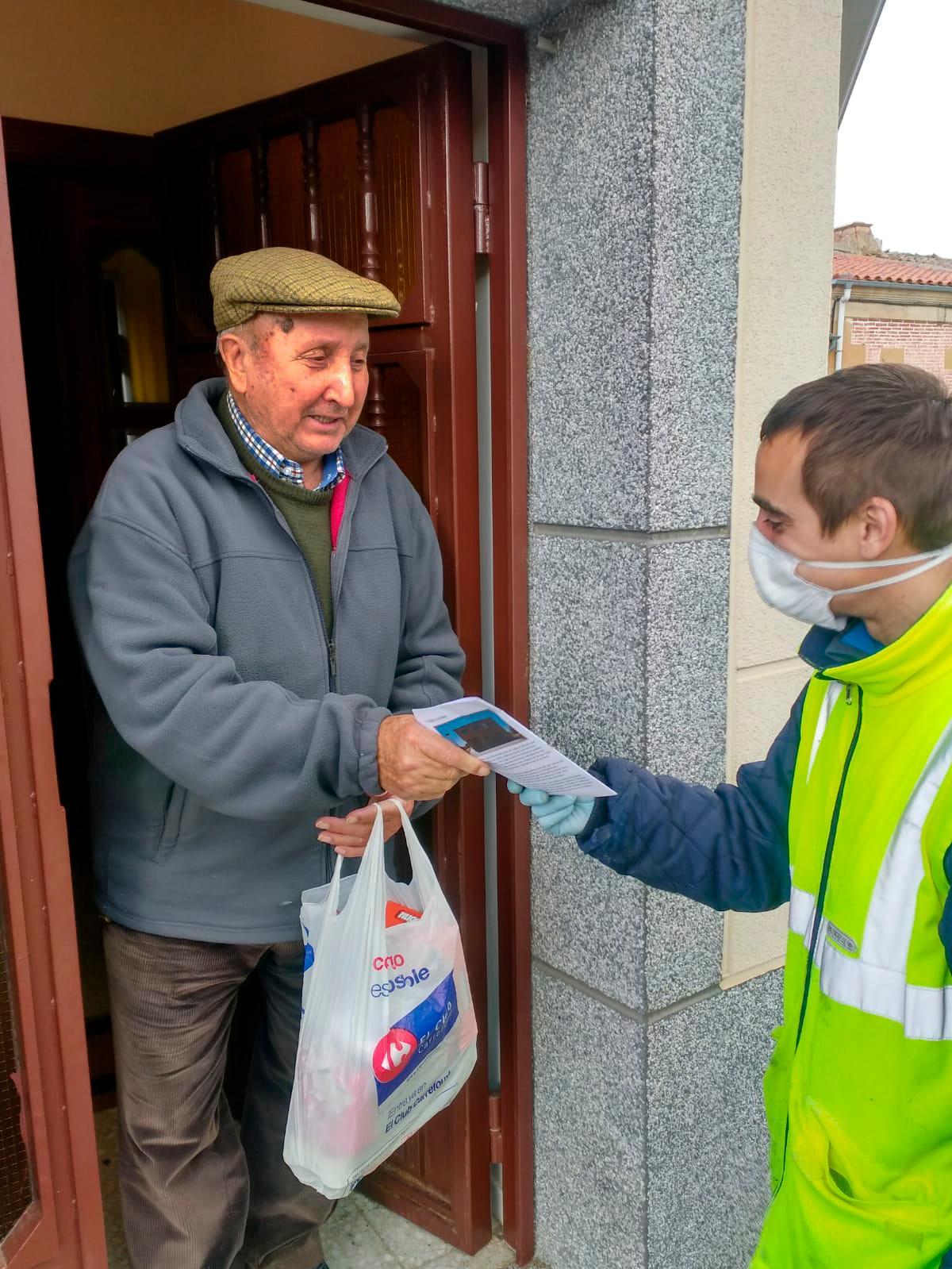 Un voluntario entrega la revista y la compra a un mayor.