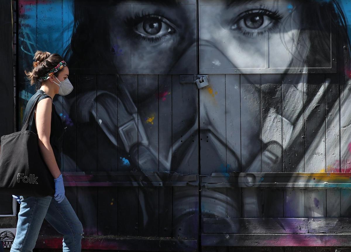 Una mujer con mascarilla y guantes en Inglaterra.