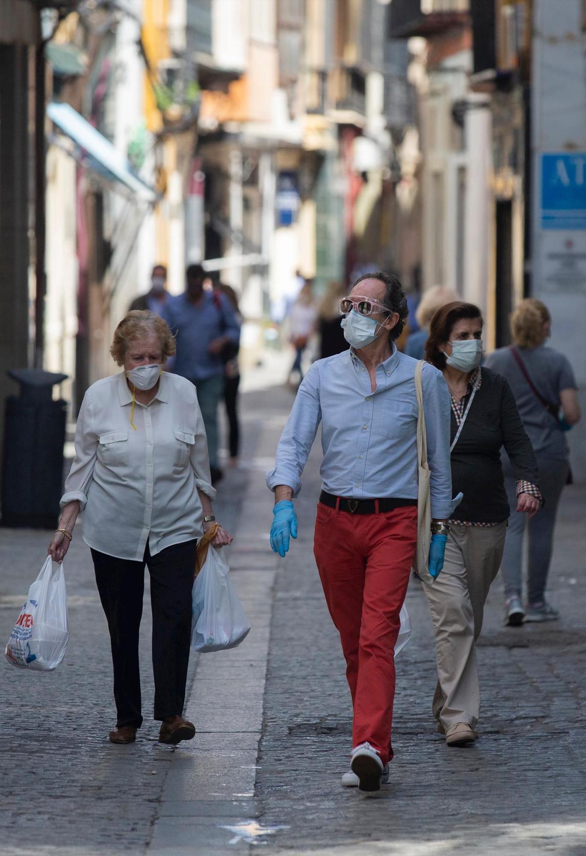 Varios ciudadanos con mascarillas por la calle.