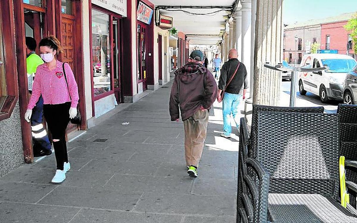 Viandantes pasando a media mañana por los soportales de la céntrica plaza de España, de Peñaranda.