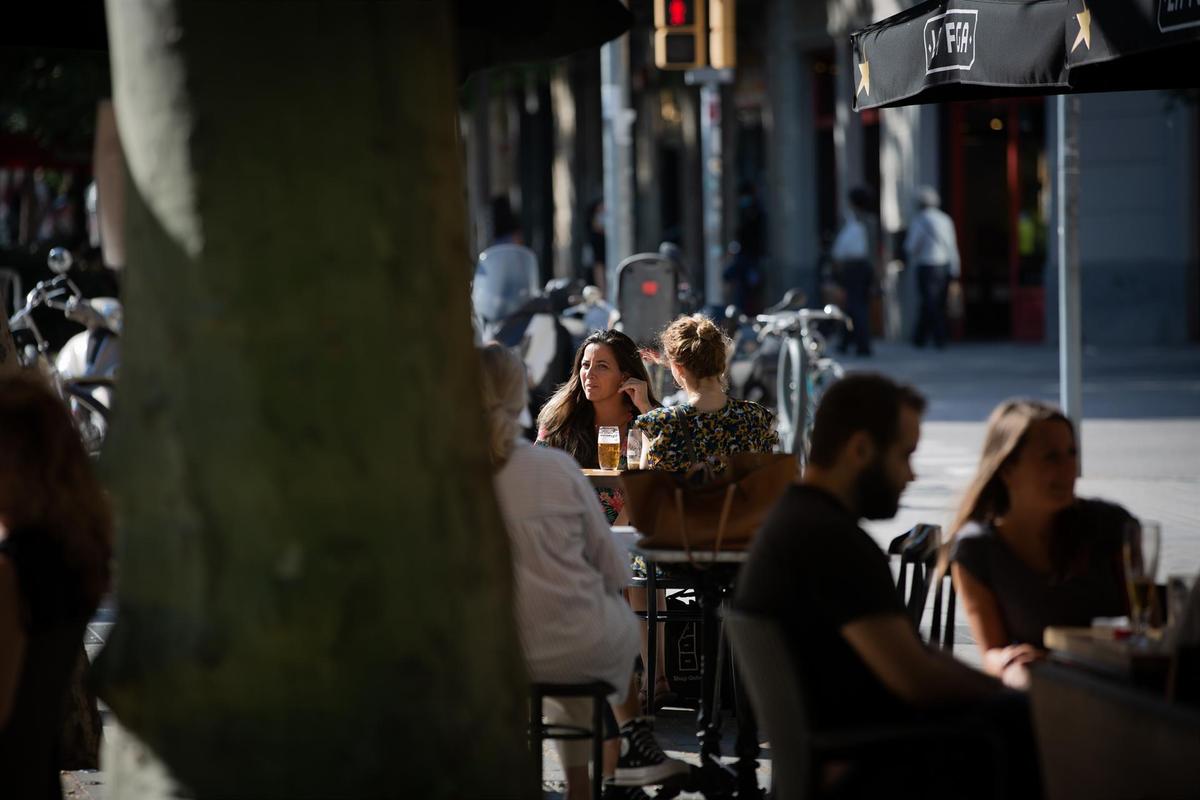 Varias personas disfrutan en la terraza de un bar.