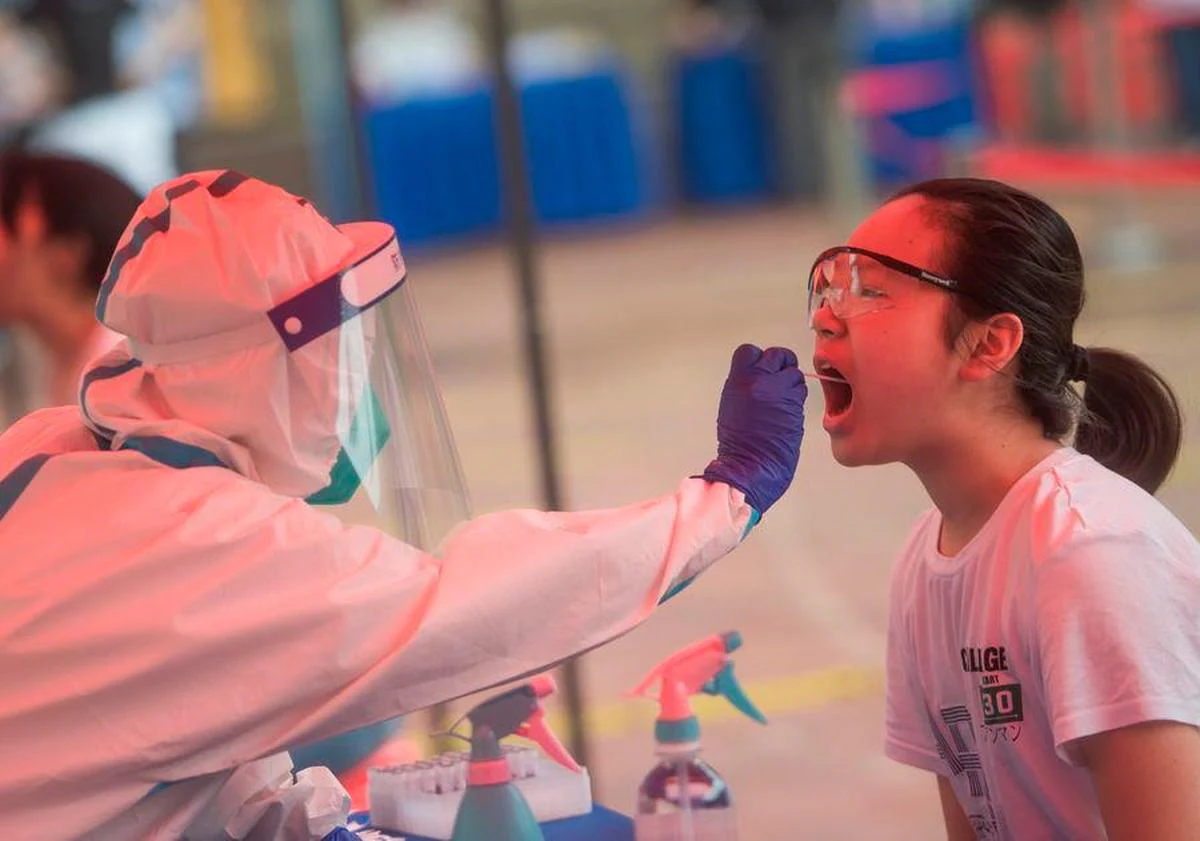 Un sanitario toma una muestra a una joven en China.