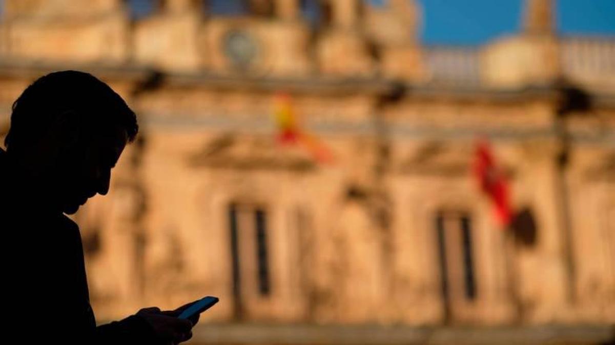 Una persona consultando su teléfono móvil en la Plaza Mayor.