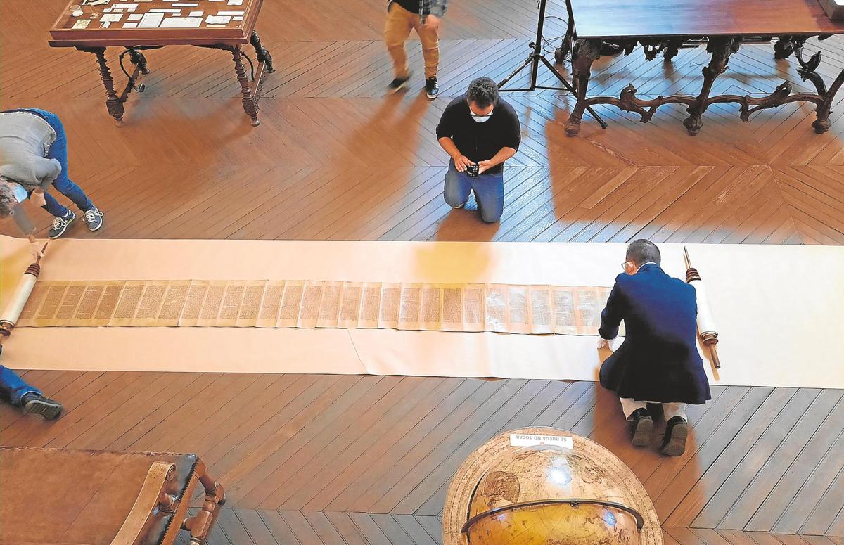 Momento en el que los trabajadores de la Biblioteca General Histórica extienden la Torá en la sala de la antigua Librería.