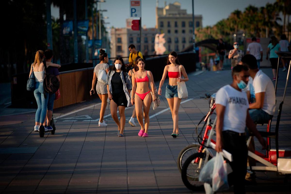 Varias jóvenes caminan en bañador por Barcelona.