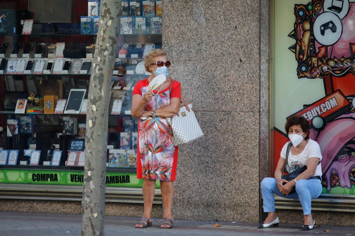 Una mujer se abanica mientras espera el autobús en Salamanca en uno de los días de mayor calor.