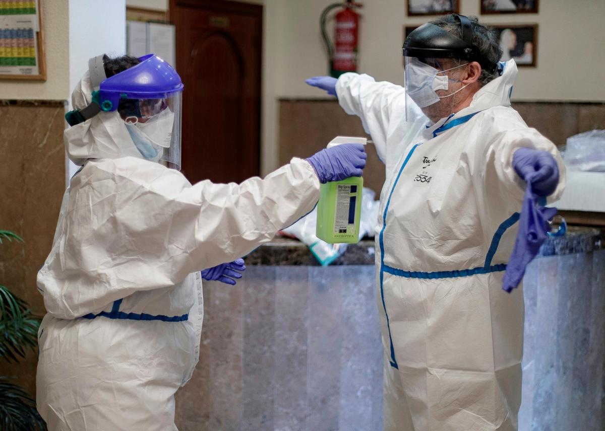 Dos sanitarios desinfectan sus trajes de protección.
