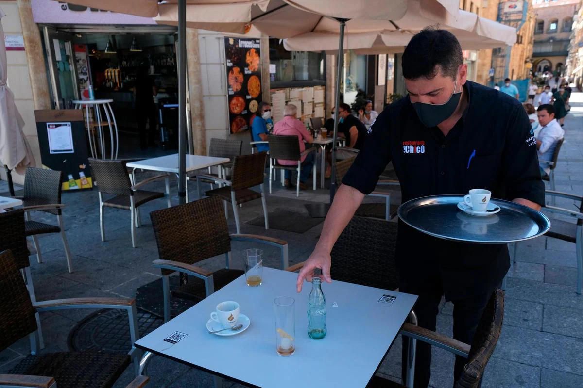 Un camarero recoge una mesa en un establecimiento de hostelería de Salamanca.