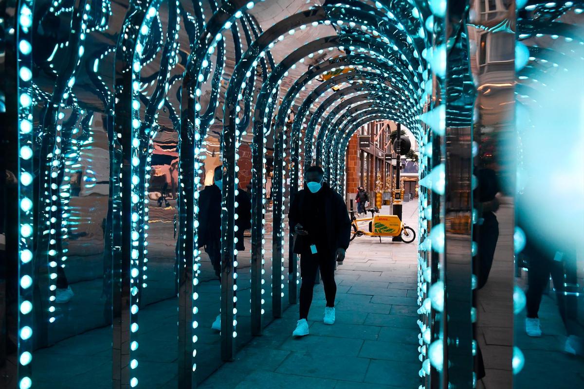Un hombre camina bajo un túnel iluminado en el Covent Garden de Londres