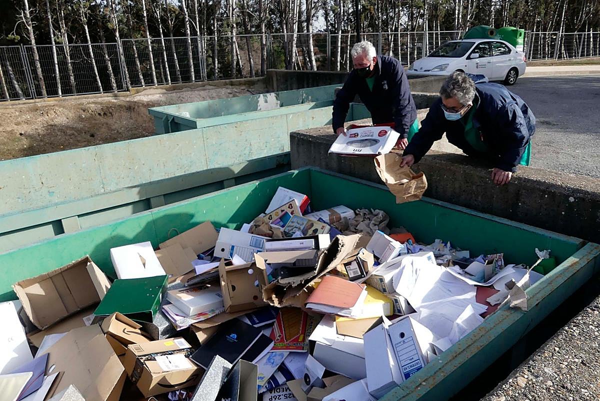 Dos operarios revisan los residuos en el contenedor de cartón.