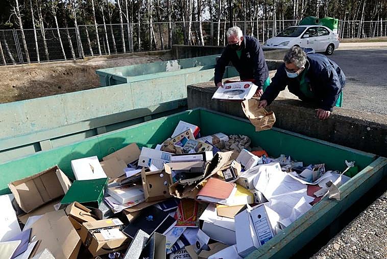 Dos operarios revisan los residuos en el contenedor de cartón.