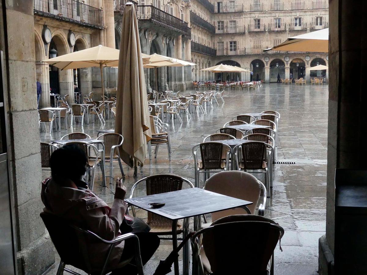 Una mujer observa la lluvia desde una terraza de la Plaza Mayor.