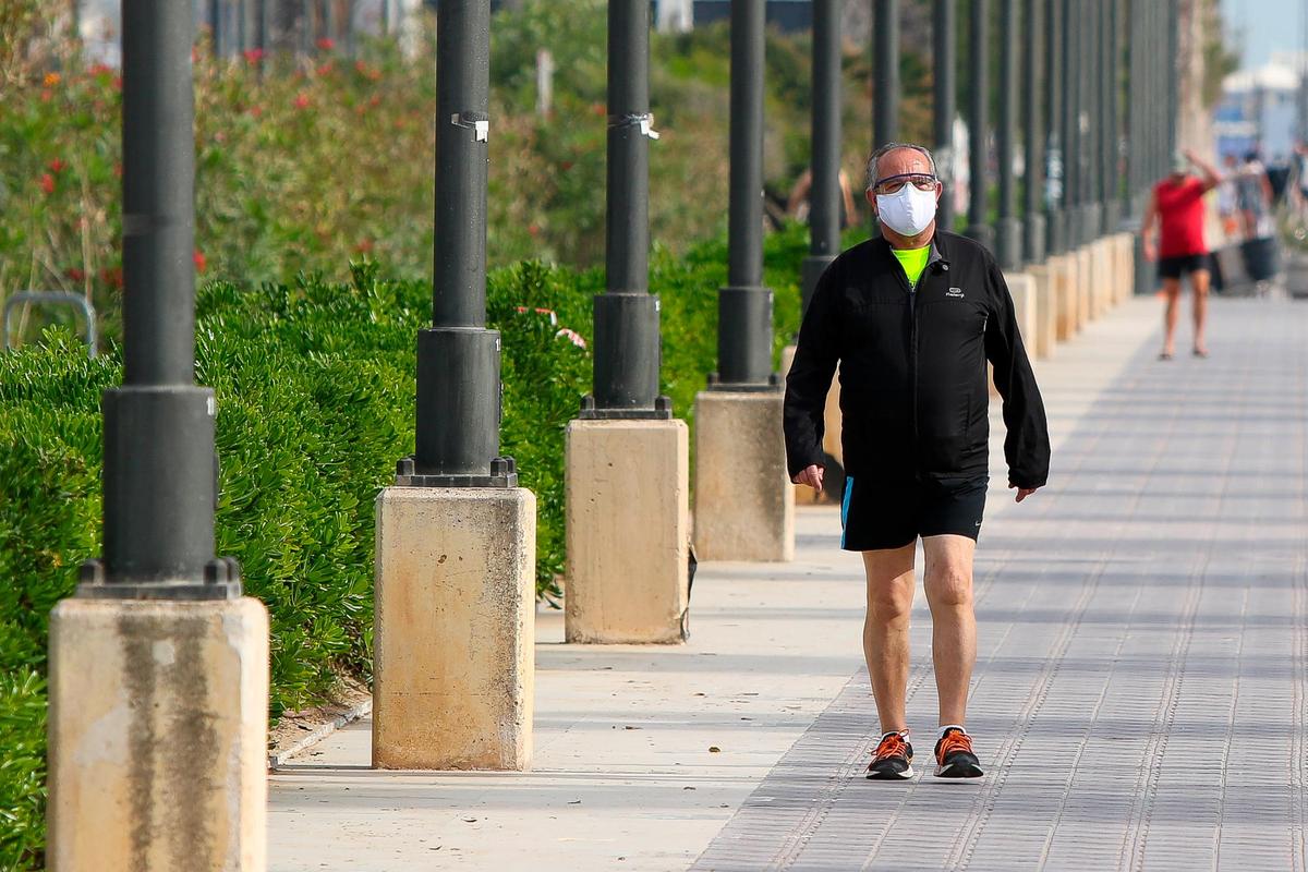 Una persona pasea por la calle con mascarilla.