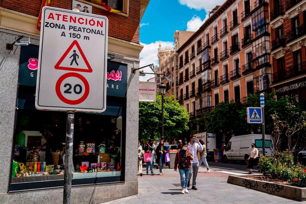 Viandantes pasan al lado de una señal que indica la limitación de la circulación a 20 km/h en una calle de Madrid.