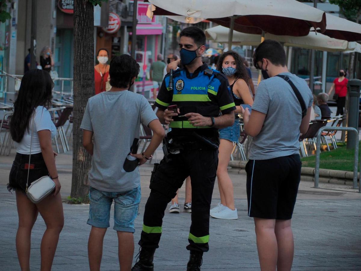 Un agente de la Policía Local de Salamanca hablando con tres jóvenes.