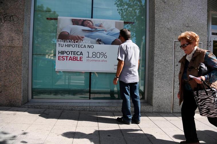 Un hombre mira el anuncio de una hipoteca en un banco.