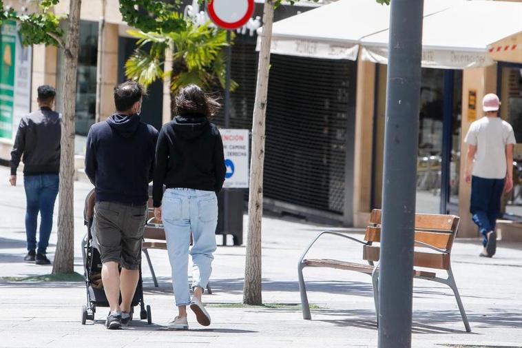 Una pareja paseando con su recién nacido por las calles de la ciudad.