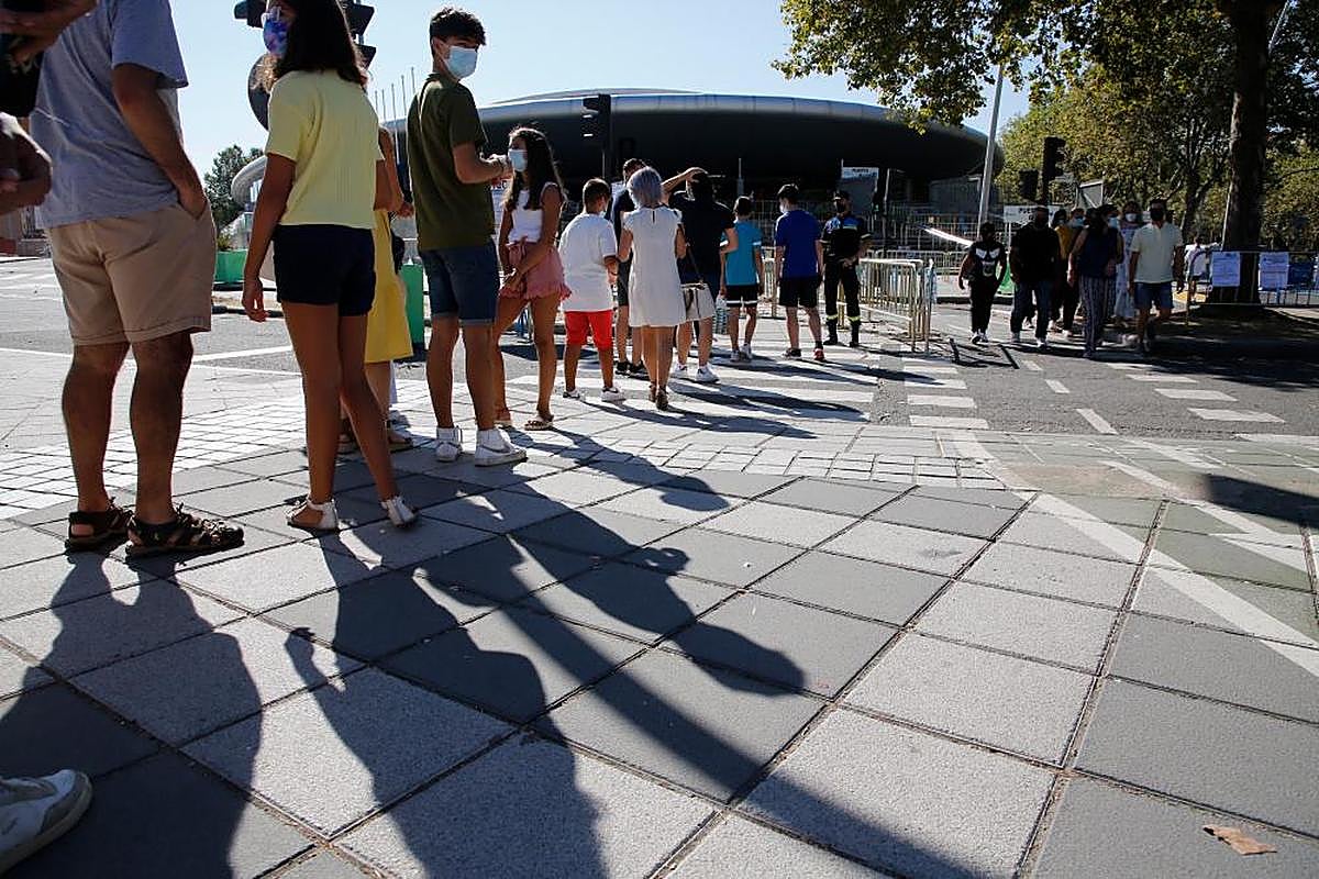 Jóvenes esperan en la cola para entrar a vacunarse en el Multiusos Sánchez Paraíso de la capital.