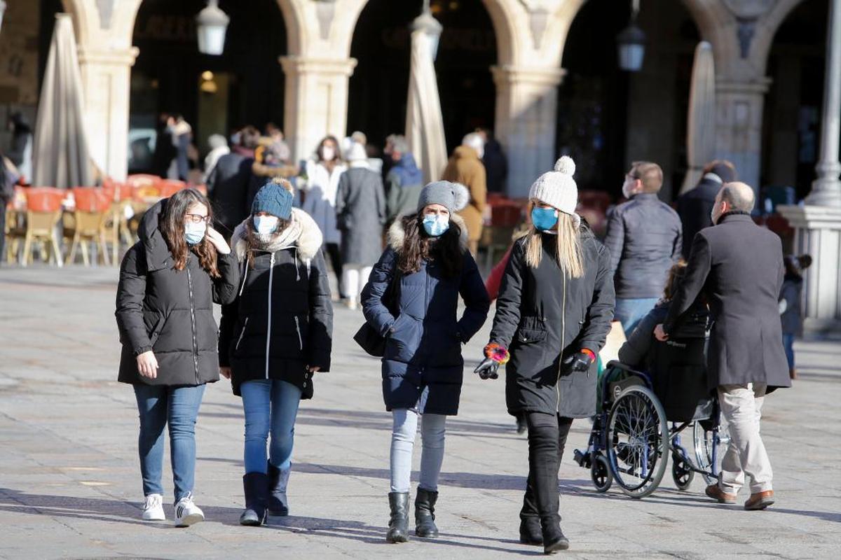 Varias jóvenes abrigadas caminan por la Plaza Mayor.