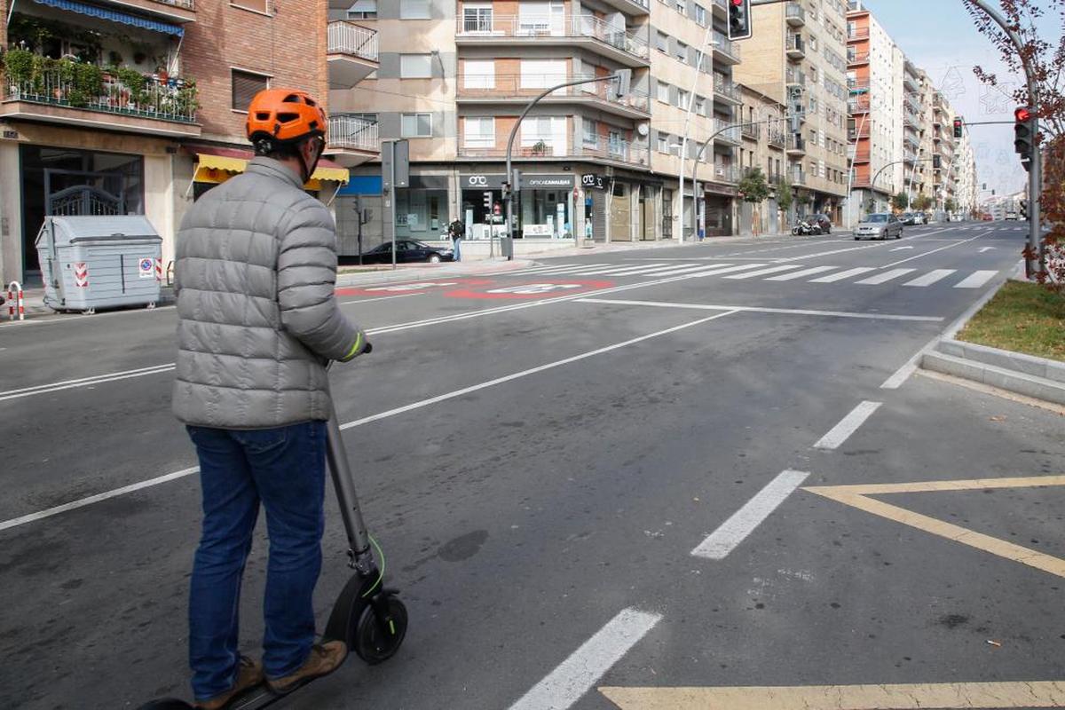 Un conductor de patinete con casco circula por la calzada en la ciudad.